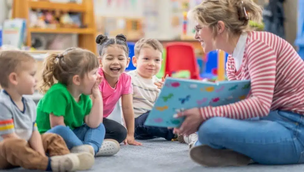 Young female kindergarten teacher reads to students at circle time.