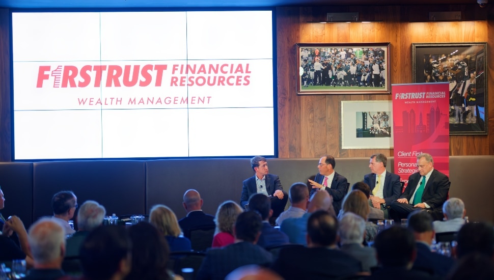 Panelists discuss finances on stage in front of audience.