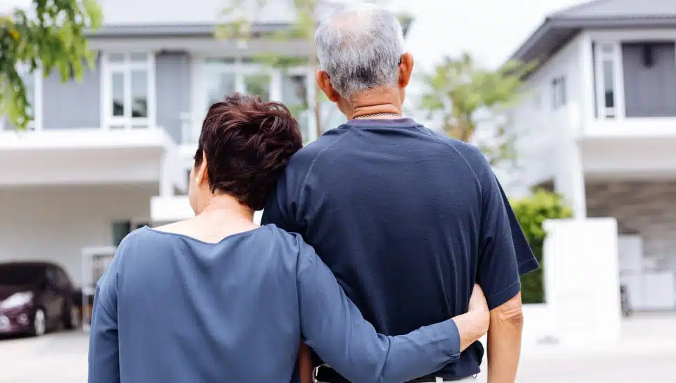 Happy senior couple from behind looking at front of house and car