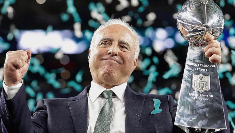 Philadelphia Eagles owner Jeffrey Lurie holds up the Lombardi trophy as green confetti falls from the sky.