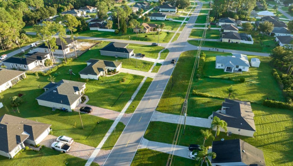 Aerial view of neighborhood with homes and cars.