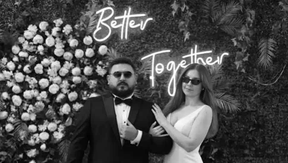 A bride and groom pose in sunglasses.