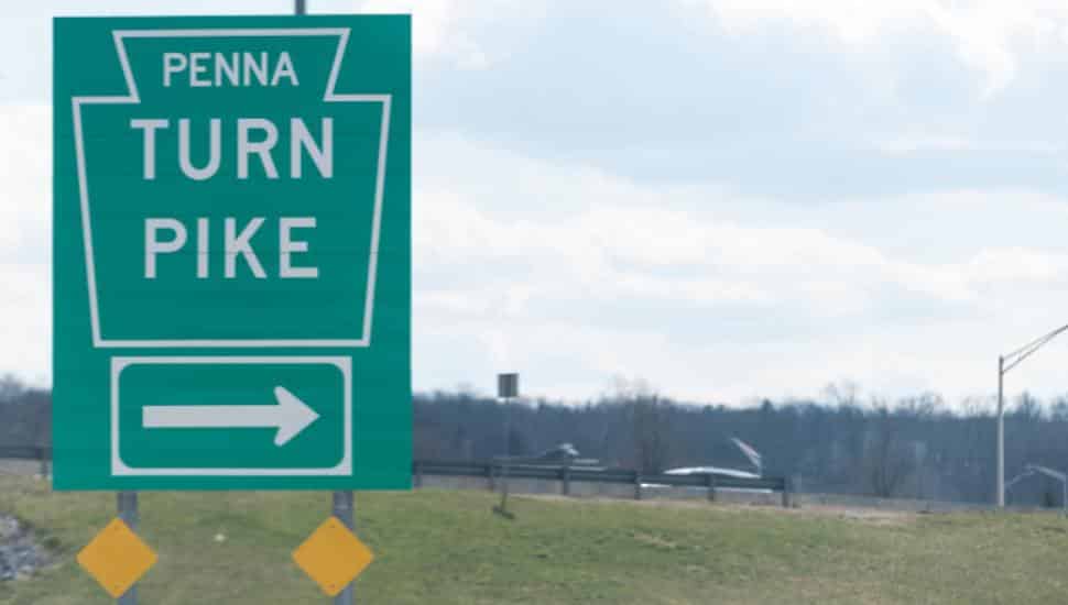 A green Pennsylvania Turnpike sign overlooks the highway.
