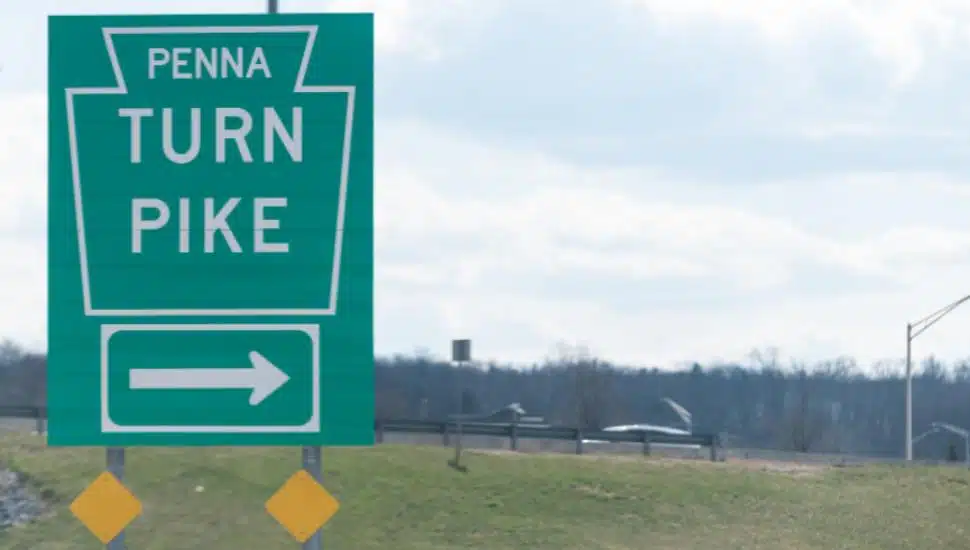 A green Pennsylvania Turnpike sign overlooks the highway.