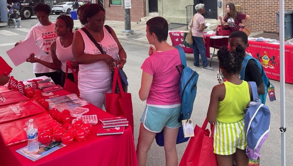 People stand underneath bank's promotional tent at community day.