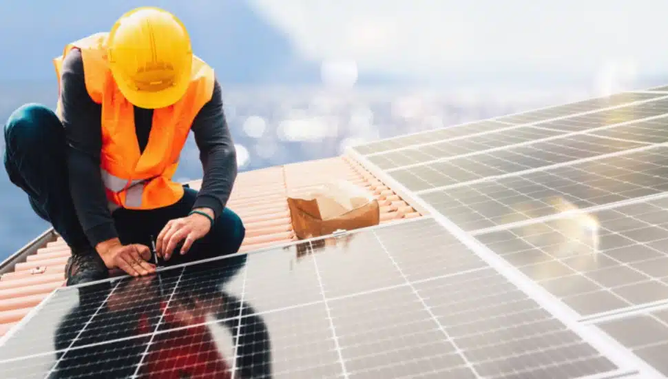 An installer puts solar panels on a houses' roof.