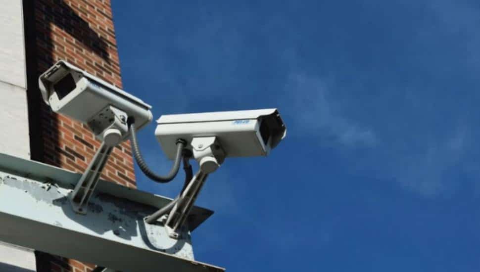 Two security cameras perch on the corner of a building.