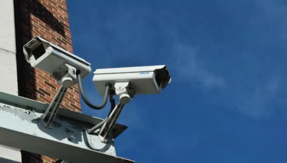 Two security cameras perch on the corner of a building.