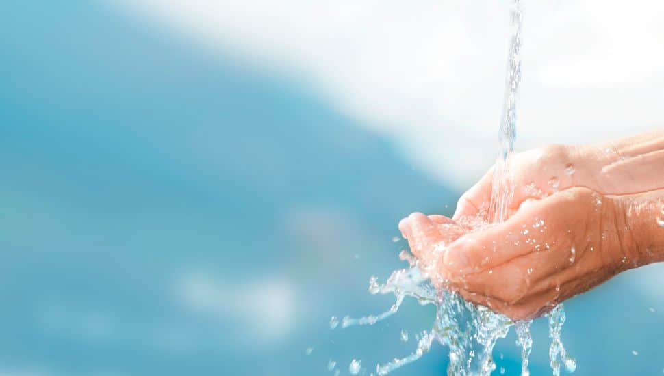 Fresh drinking water flows over human hands.