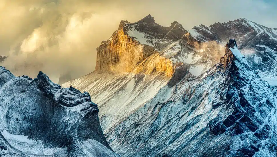 Dramatic snow-covered mountain peaks in golden sunlight, photographed by Vince Pellegrini, part of the Berks Photographic Society Members Exhibition at Montgomery County Community College.