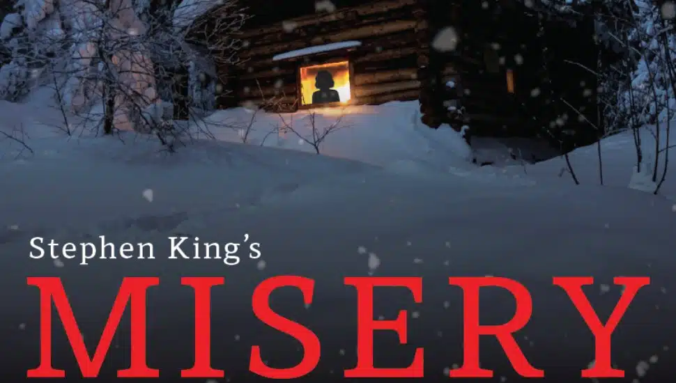 Snow-covered cabin in the woods with a shadowy figure seen through a glowing window. Large red text reads ‘Stephen King’s Misery.’ Promotional poster for Act II Playhouse production.