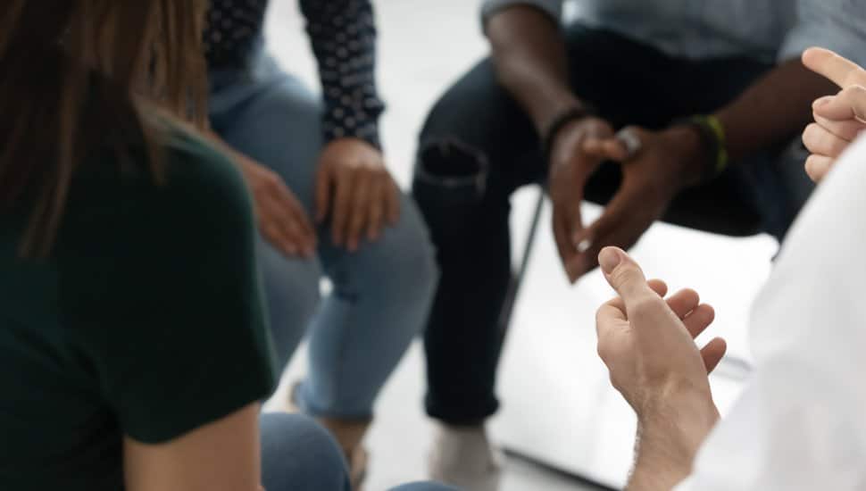 A group sits in a circle to comfort someone dealing with grief.