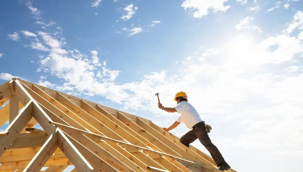 A home builder works on a roof.
