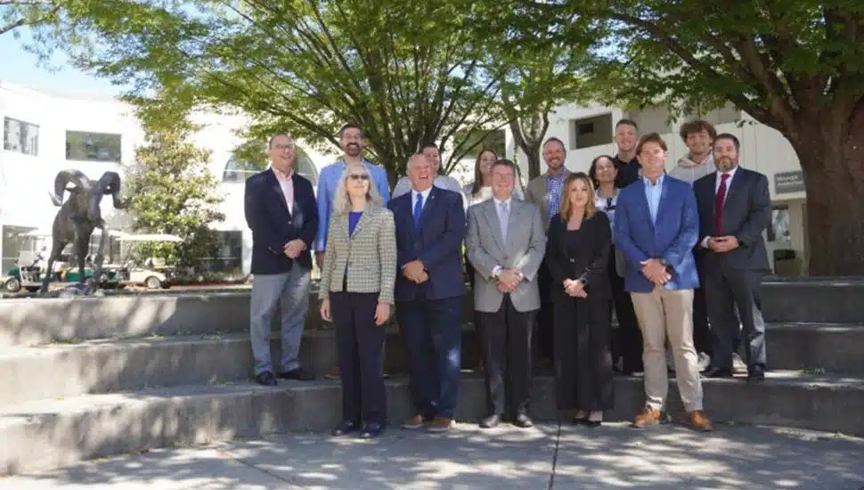 School administrators and students pose for a group photo on steps.