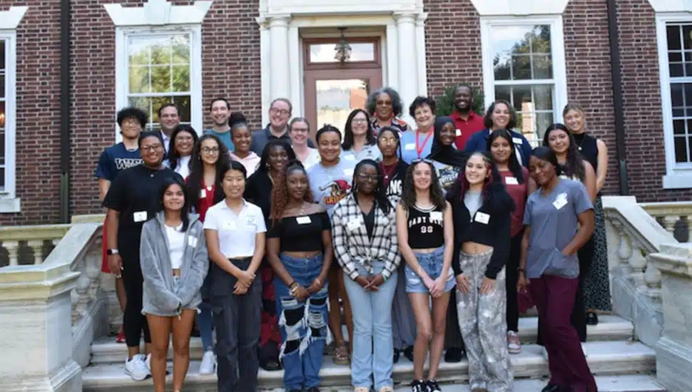 Group of college students pose for picture on building steps.