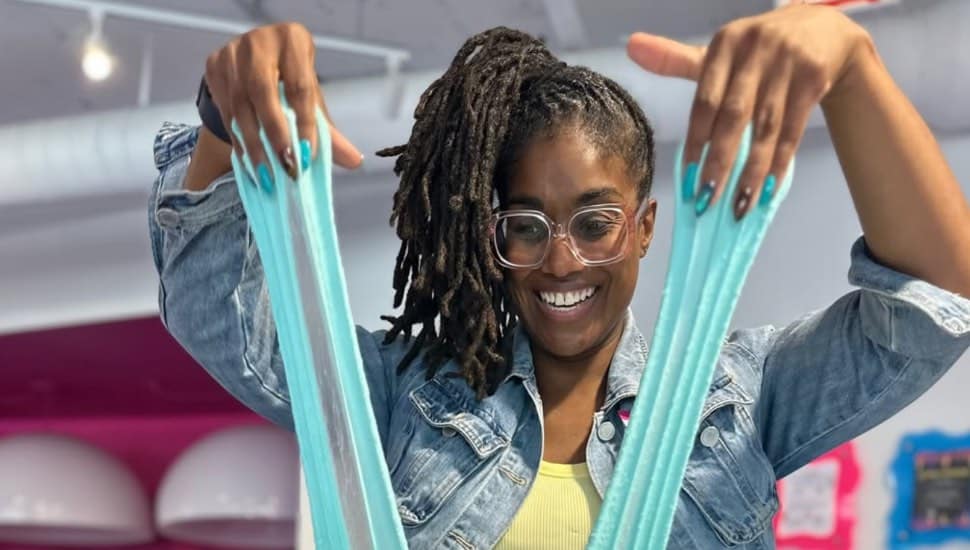 A woman plays with slime at the Sloomoo Institute