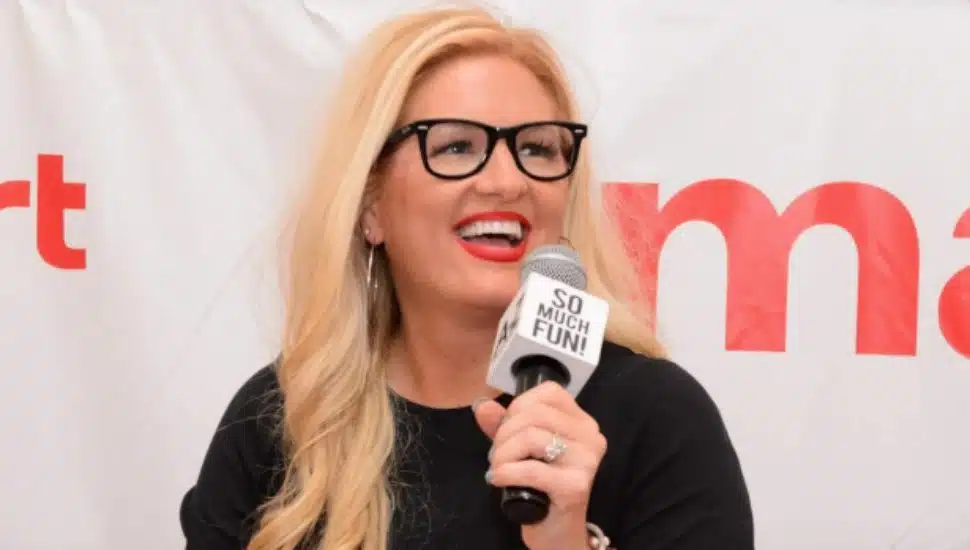 David's Bridal CEO Kelly Cook smiles while speaking into a microphone.