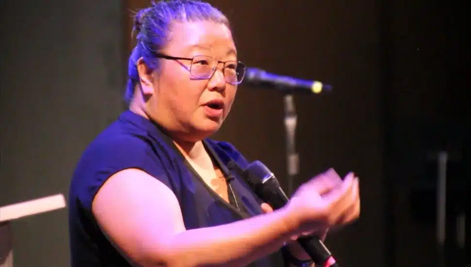 Middle-aged female speaker talks into microphone.