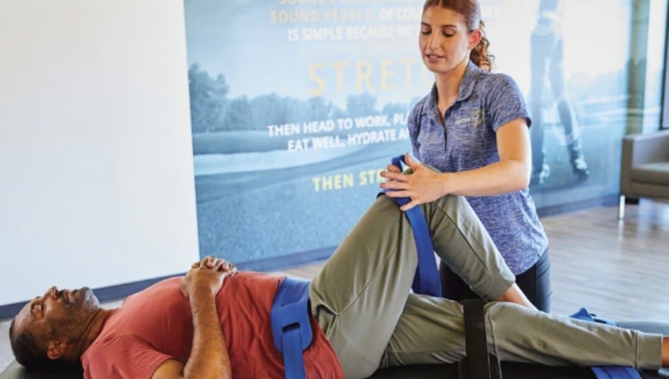 A Stretch Zone specialist helps a man stretch.