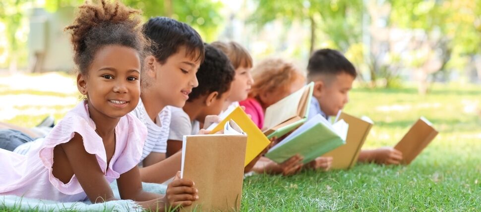 Children lie on the grass reading books.