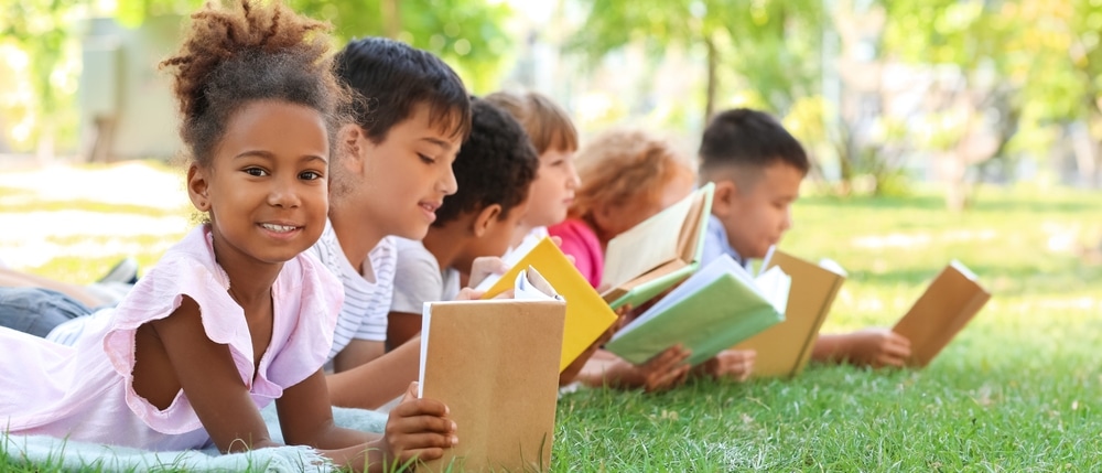 Children lie on the grass reading books.