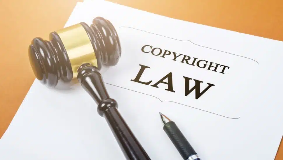 A paper with the title "Copyright Law" written on it, with a gavel and a pen resting on the paper.