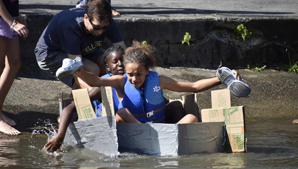 Middle school students float in cardboard boat.