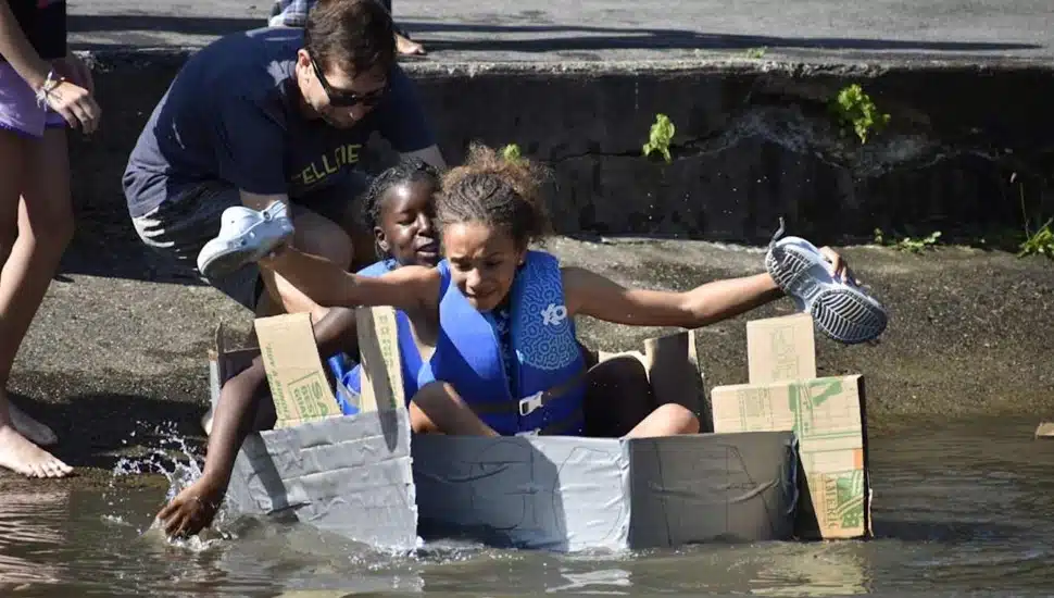 Middle school students float in cardboard boat.