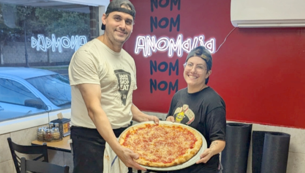 Owners Frank and Deena hold up an Anomalia Pizza.