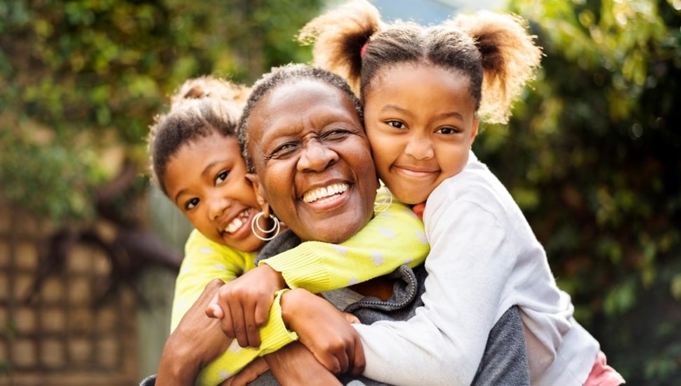 Two young girls hug their grandmother.