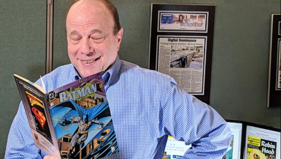 Jim Drucker reads from a Batman comic in a cubicle.