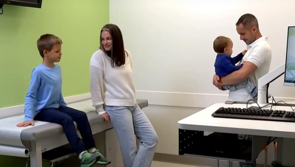 Landon Gallo sits in the doctor's office with his mom, dad, and brother.