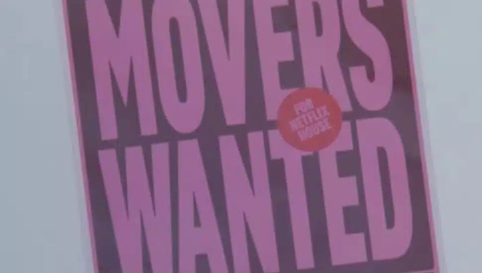 A Movers Wanted poster for Netflix House hangs on a wall.