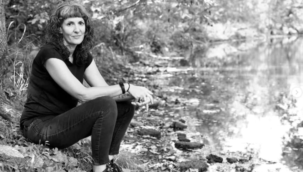 Rebecca Schultz sits by a stream.