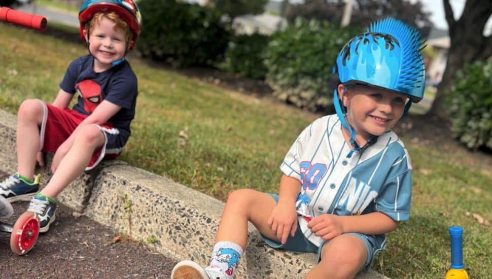 Two boys sit on a curb after the Goddard School Trike-A-Thon.