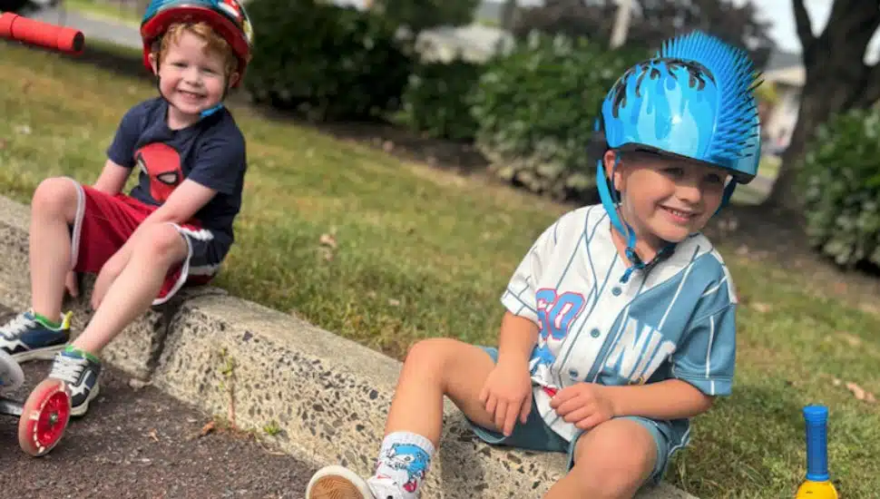 Two boys sit on a curb after the Goddard School Trike-A-Thon.