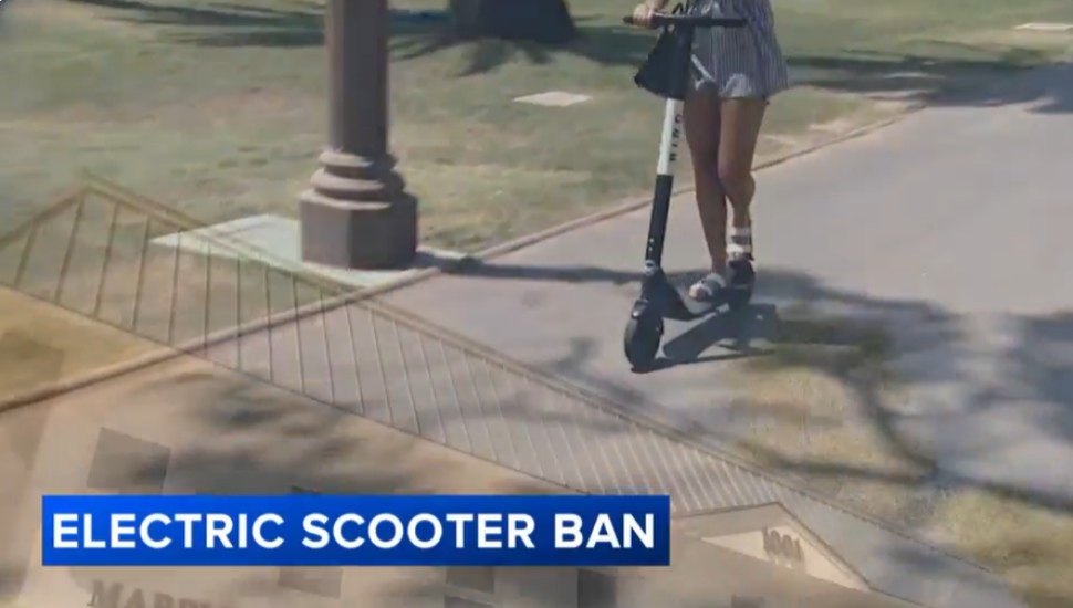 A girl rides an e-scooter on the sidewalk.