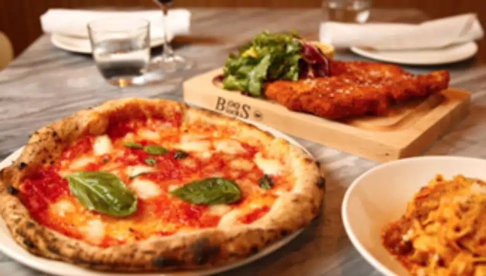 An Italian meal spread featuring Neapolitan-style Margherita pizza, breaded cutlet with salad, and a pasta dish, served at Eataly King of Prussia.