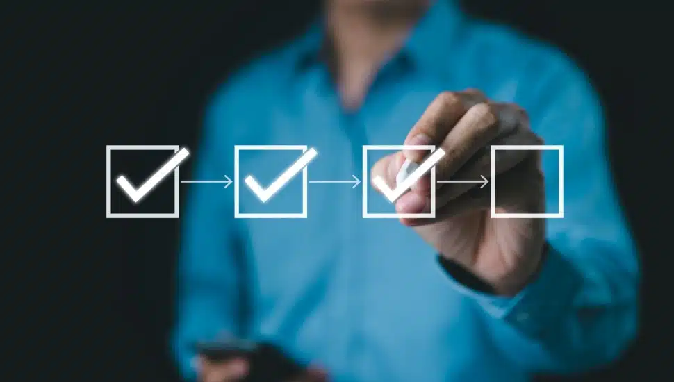Businessman checks boxes on digital checklist.