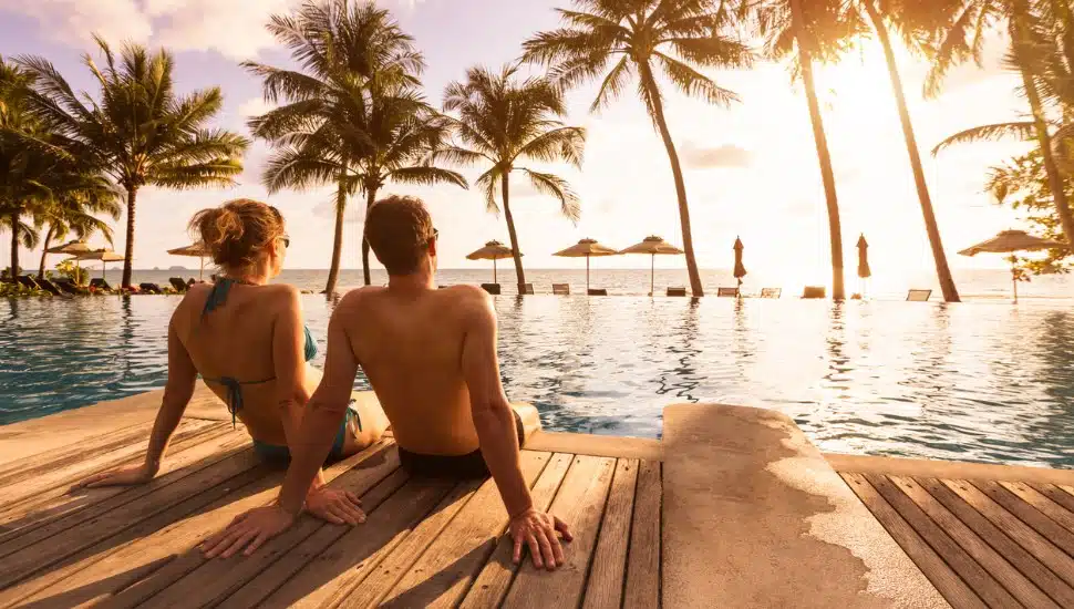 Couple enjoying beach vacation holidays at tropical resort with swimming pool.