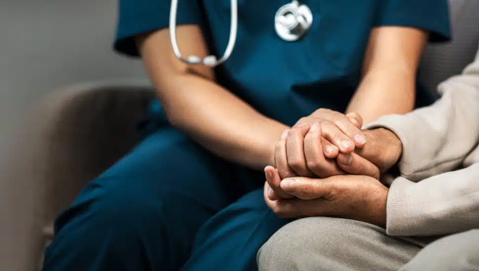A female nurse caregiver holds hands to encourage and comfort an elderly woman. For care and trust in nursing homes for people of retirement age Caregiver helping elderly woman provides medical advice
