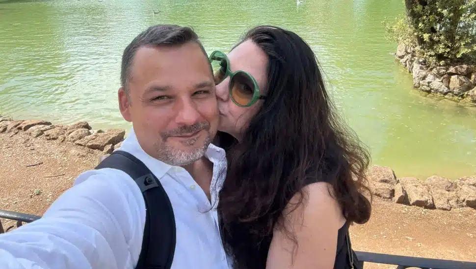 Michelle Lordi kisses Matthew Parrish on the cheek in front of water.