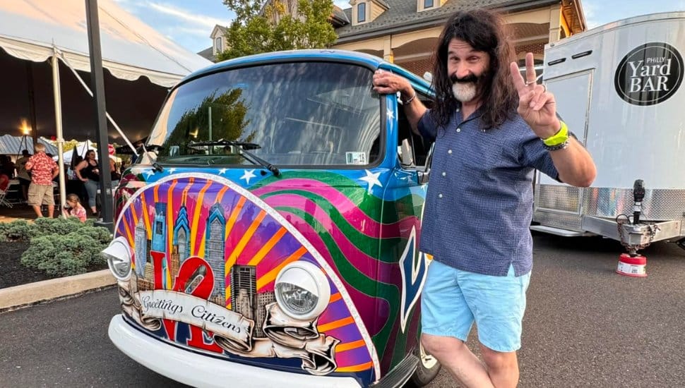 Pierre Robert offers the epace sign, standing next to his Volkswagen RV.