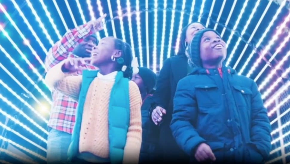 A family walks through a tunnel of lights at the Elmwood Park Zoo.