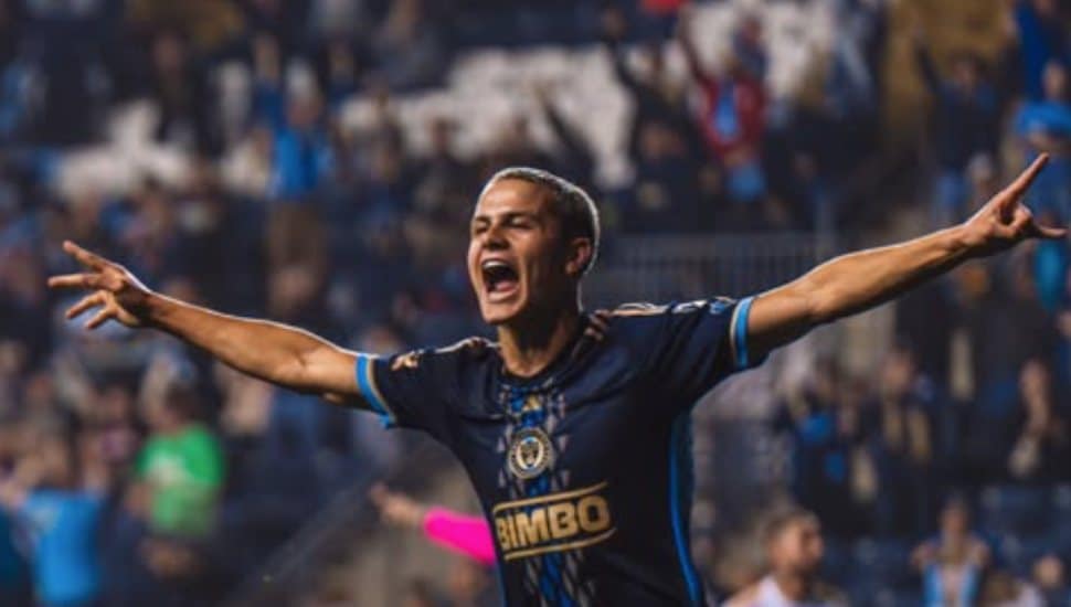 Cavan Sullivan spreads his arms in celebration on the soccer pitch.