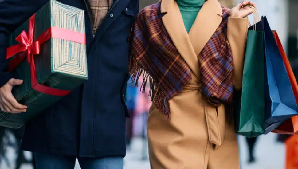 Two people walk down the street with holiday gifts.