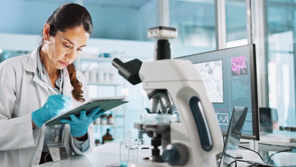 A lab technician monitors a microscope.