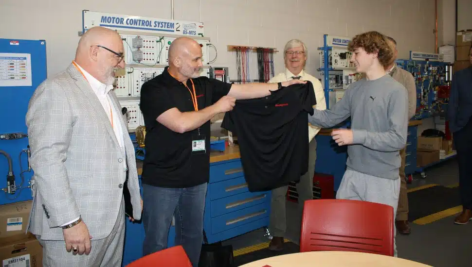 Company representatives hand shirt to new employee.
