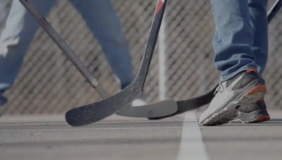 A close-up of men in sneakers and hockey sticks.
