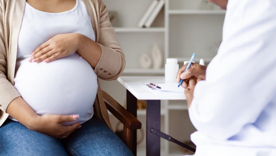 Obstetrician listens to pregnant patient.